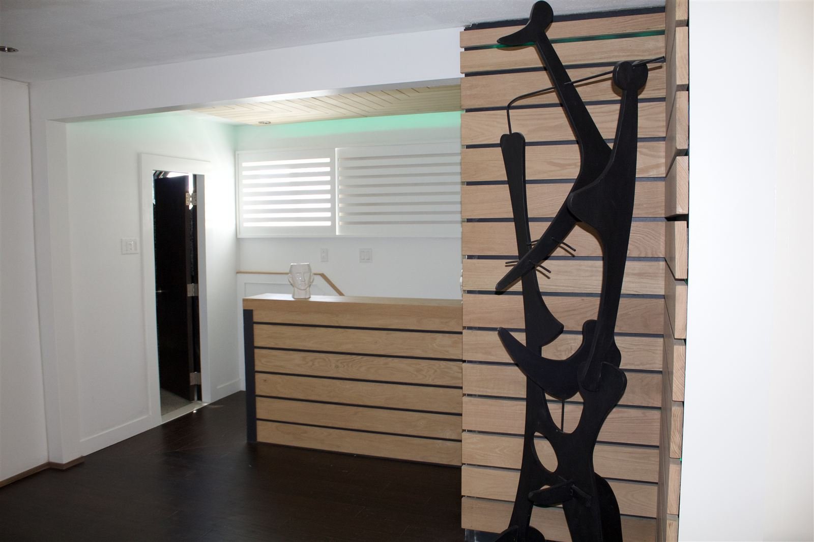 White oak slat bar and reception wall with CNC-cut sculptural screen
