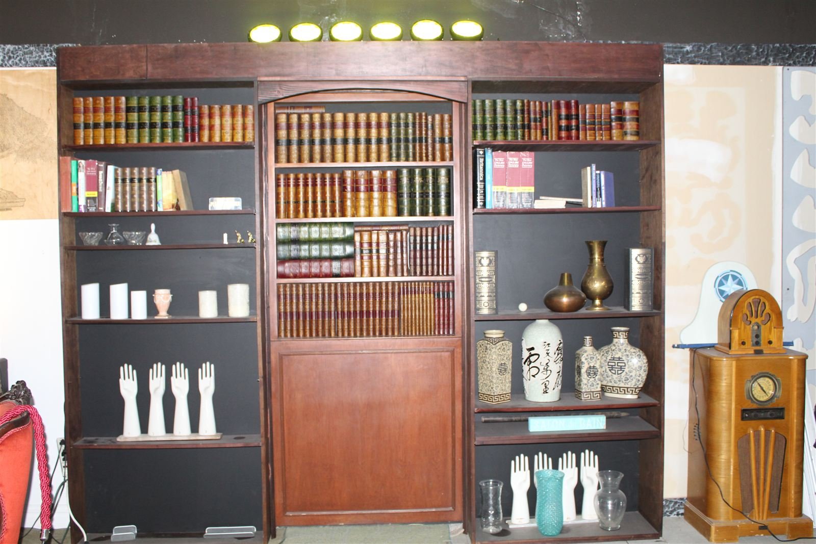 Hidden speakeasy door disguised as a full bookcase wall, shown open to a corridor